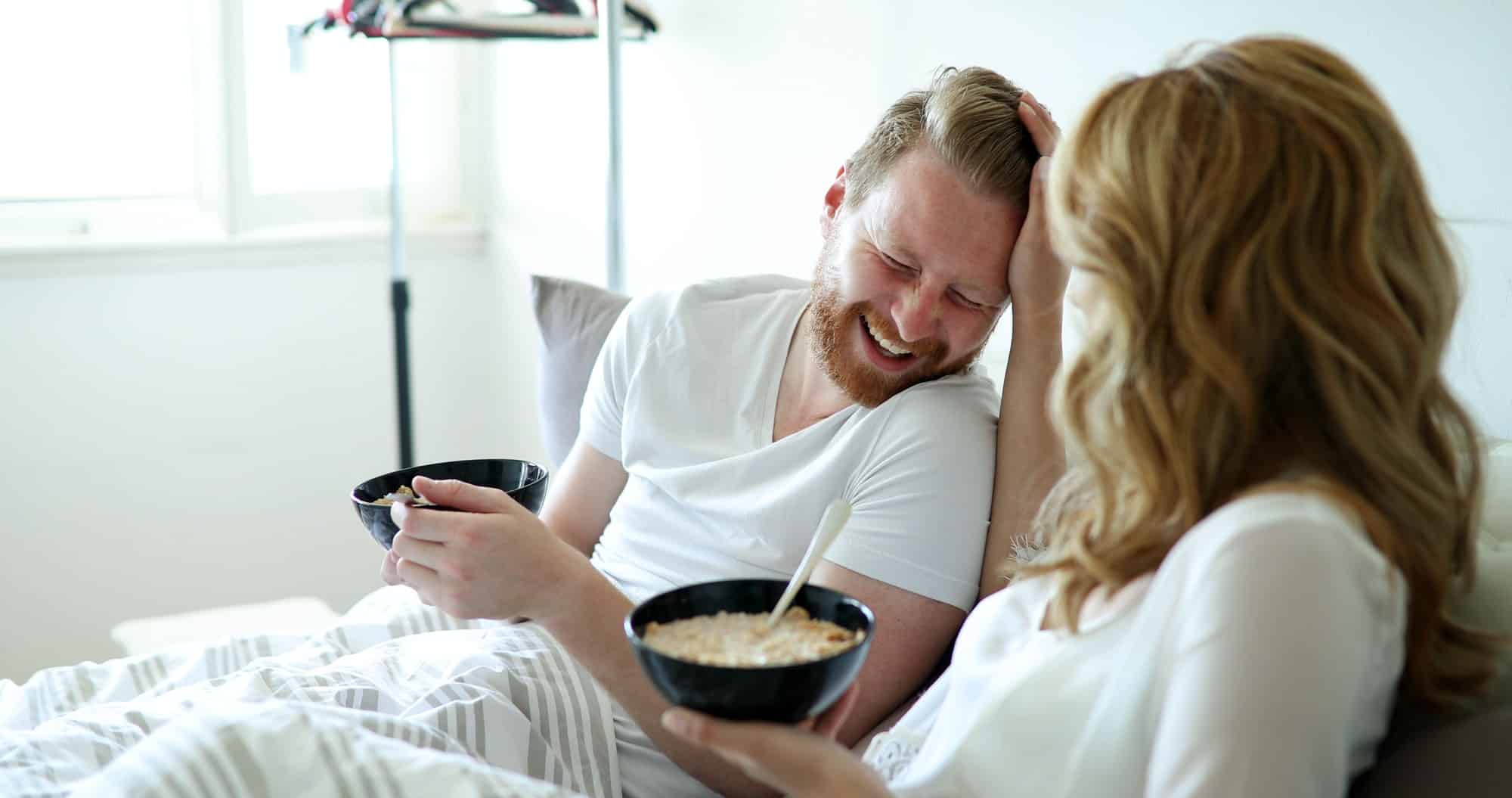Young attractive couple having breakfast in bed